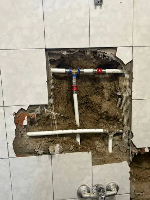 Feltárt és kijavított vízvezetékcső csempézett falban egy terézvárosi társasházban